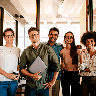 Equipe de trabalho olha pra frente e sorri.